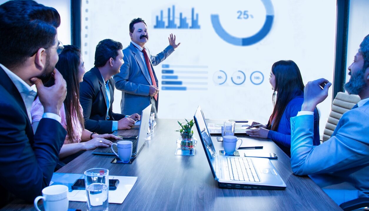 Indian business people meeting presentation in office conference room showing Infographics graphs on projector screen, Revenue growth strategy and analysis.Product sales.